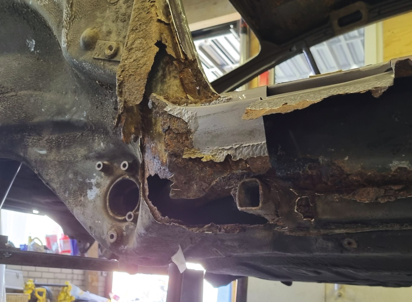 Roest en structuurschade aan het onderstel van een klassieke auto in de werkplaats